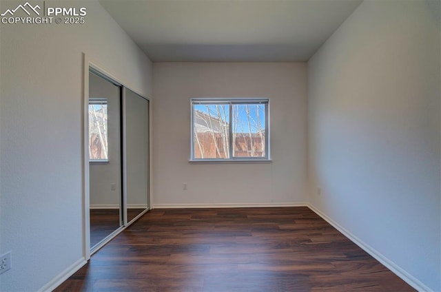 unfurnished bedroom featuring a closet, baseboards, and dark wood-type flooring