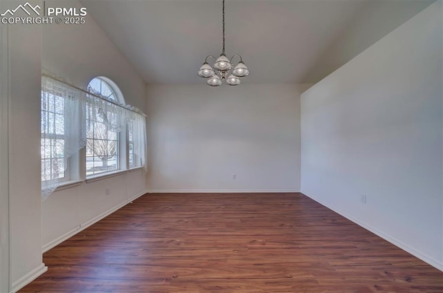 empty room featuring a chandelier, lofted ceiling, baseboards, and wood finished floors