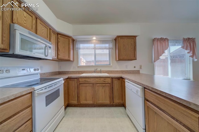 kitchen featuring light countertops, white appliances, brown cabinetry, and a sink