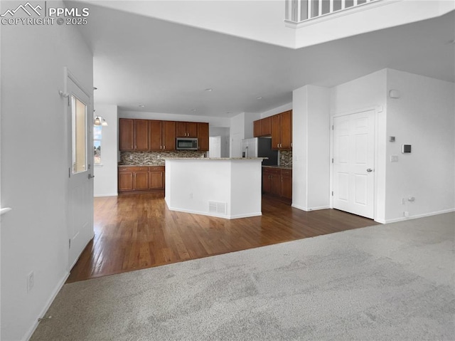 kitchen featuring a center island, appliances with stainless steel finishes, dark colored carpet, and decorative backsplash