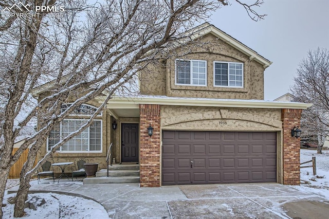 traditional home featuring a garage, stucco siding, concrete driveway, and brick siding