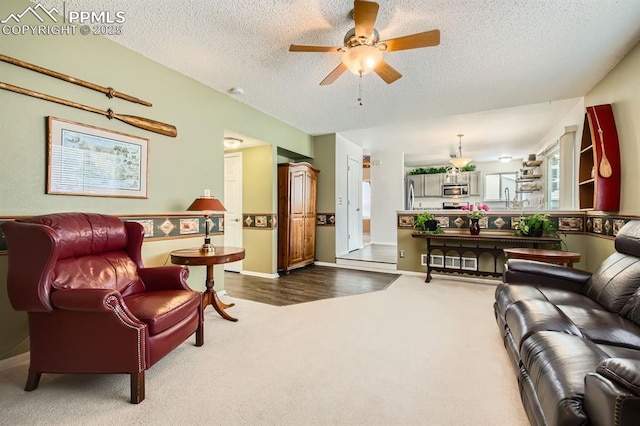 living area featuring a textured ceiling, carpet floors, a ceiling fan, and a healthy amount of sunlight