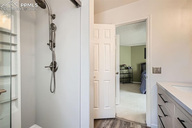 full bath featuring wood finished floors, a shower stall, vanity, and ensuite bathroom