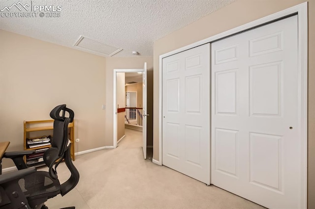 home office with light carpet, a textured ceiling, attic access, and baseboards