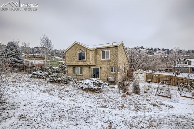 snow covered back of property with a fenced backyard