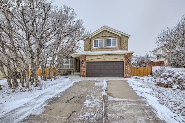 traditional-style home featuring a garage, fence, concrete driveway, and brick siding