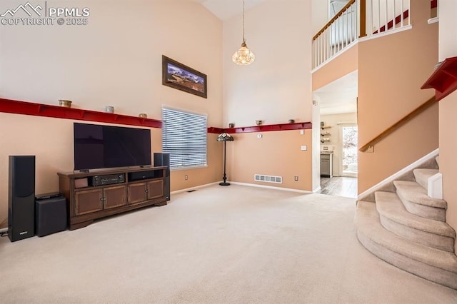 living area featuring carpet, visible vents, stairway, a towering ceiling, and baseboards