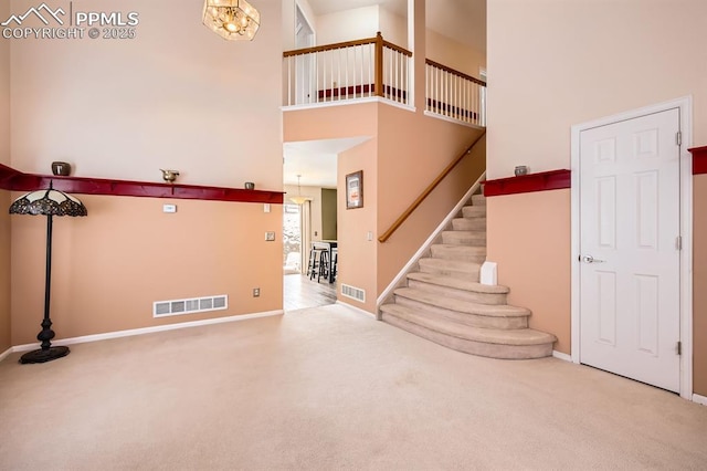 carpeted entryway featuring stairway, a towering ceiling, visible vents, and baseboards