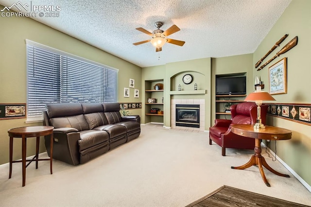 living room featuring a textured ceiling, a tile fireplace, a ceiling fan, baseboards, and carpet