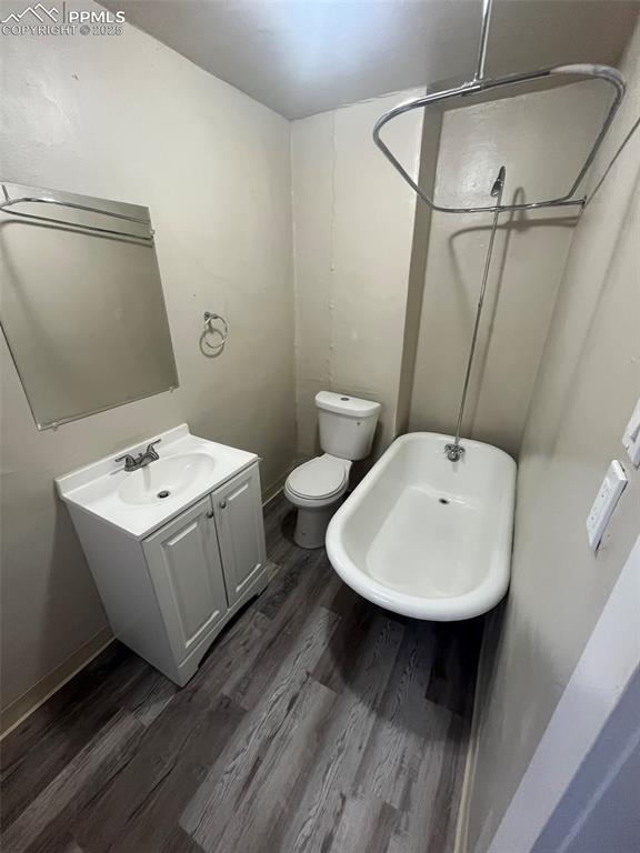 full bathroom with toilet, a shower, wood finished floors, and vanity