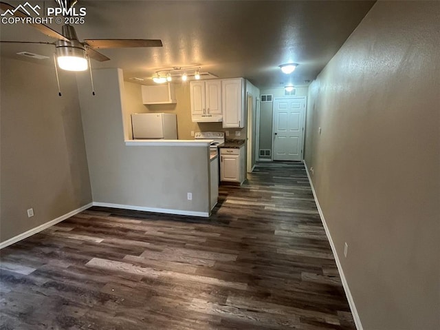 kitchen with under cabinet range hood, white appliances, white cabinets, baseboards, and dark wood finished floors