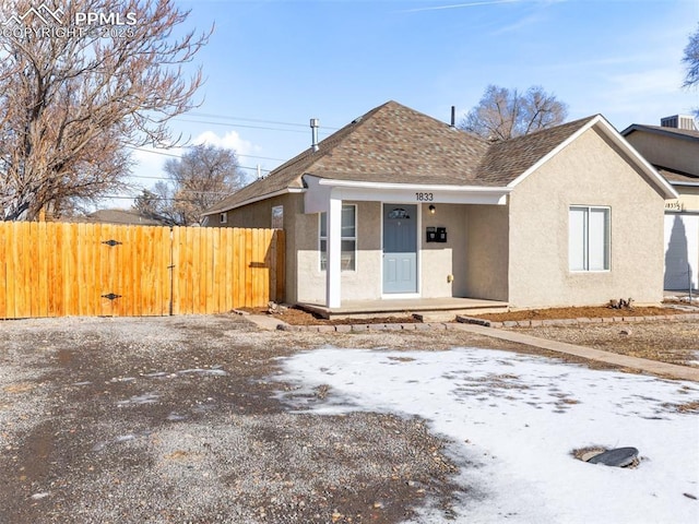 view of front of property with a gate, roof with shingles, fence, and stucco siding