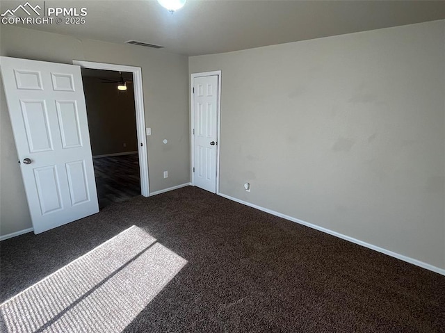 unfurnished bedroom featuring a closet, visible vents, dark carpet, and baseboards