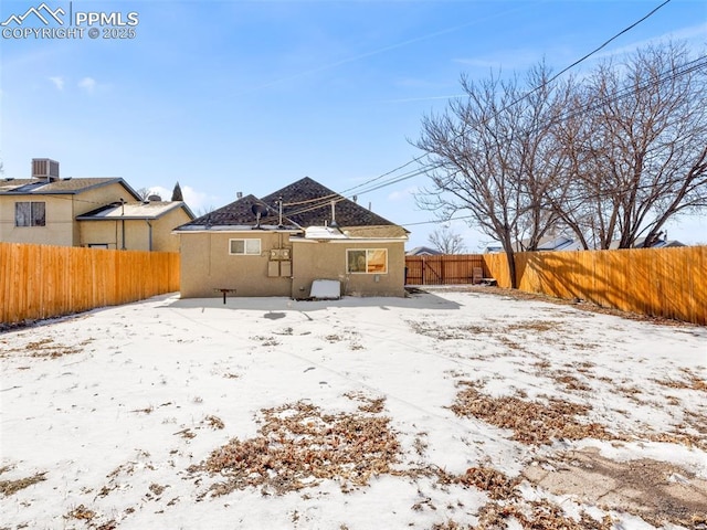 snow covered back of property with a fenced backyard and central AC