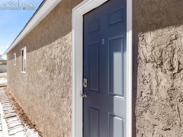 entrance to property featuring stucco siding