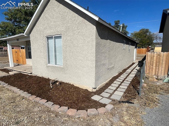 view of side of property featuring fence and stucco siding