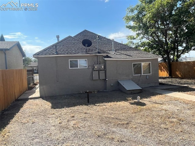 rear view of property featuring fence and stucco siding