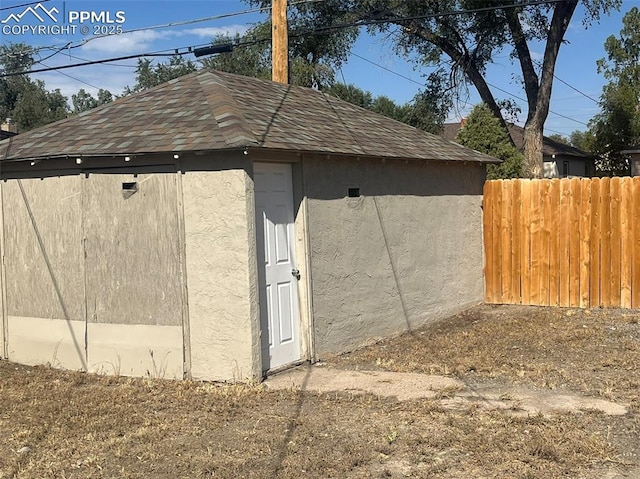 view of outdoor structure with fence and an outbuilding