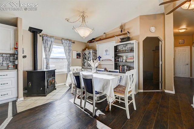 dining area featuring hardwood / wood-style floors, a wood stove, lofted ceiling, and ceiling fan