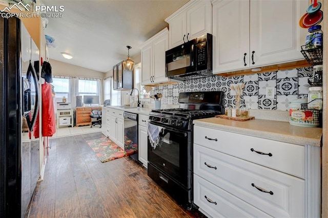 kitchen featuring vaulted ceiling, sink, white cabinetry, decorative light fixtures, and black appliances