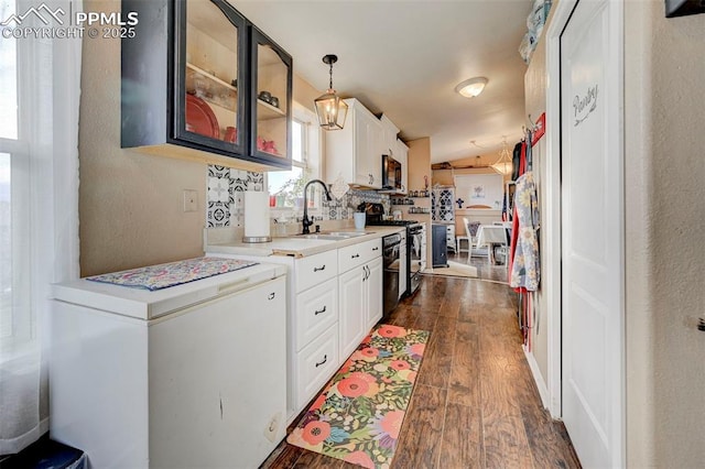 kitchen with hanging light fixtures, black appliances, dark hardwood / wood-style flooring, sink, and white cabinetry