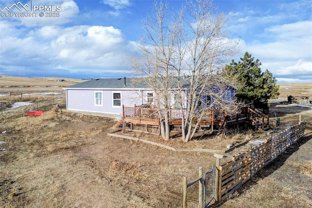 back of property with a deck and a rural view