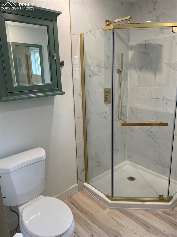 bathroom with toilet, hardwood / wood-style flooring, and an enclosed shower