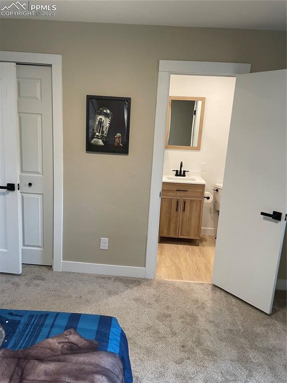 carpeted bedroom featuring sink, a closet, and connected bathroom