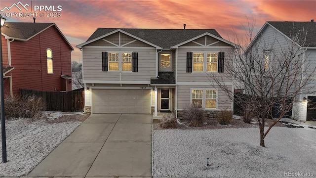 view of front of home with a garage, concrete driveway, roof with shingles, and fence