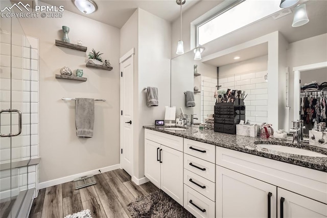 bathroom with hardwood / wood-style flooring, a shower with shower door, and vanity