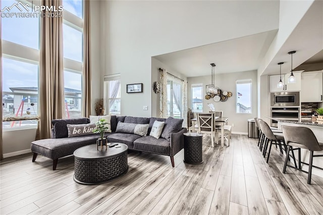 living room with light hardwood / wood-style flooring, an inviting chandelier, and a towering ceiling