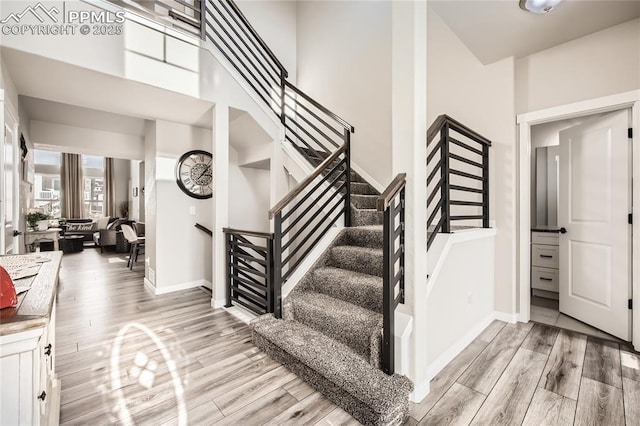 stairs featuring wood-type flooring and a high ceiling