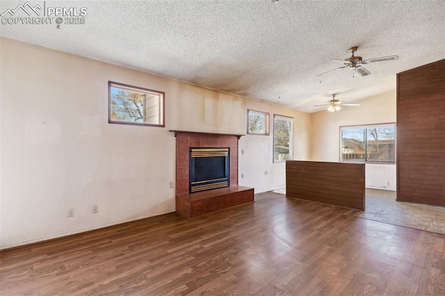 unfurnished living room featuring baseboards, wood finished floors, vaulted ceiling, a textured ceiling, and a fireplace