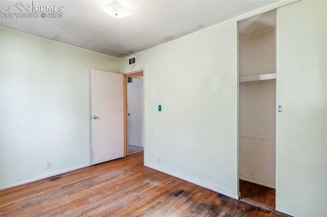 unfurnished bedroom featuring a closet, visible vents, baseboards, and hardwood / wood-style flooring