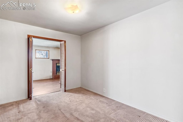 carpeted spare room with a fireplace and baseboards