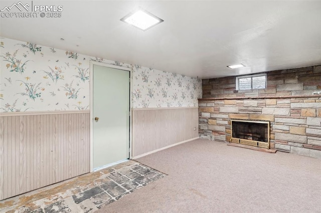 unfurnished living room with wallpapered walls, a fireplace, a wainscoted wall, and carpet flooring