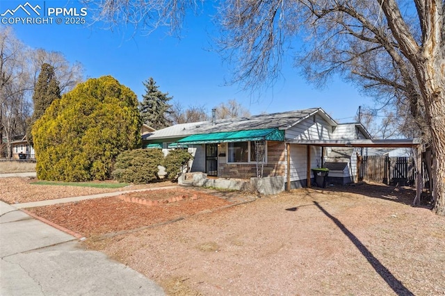 view of front of property with dirt driveway, fence, and an attached carport