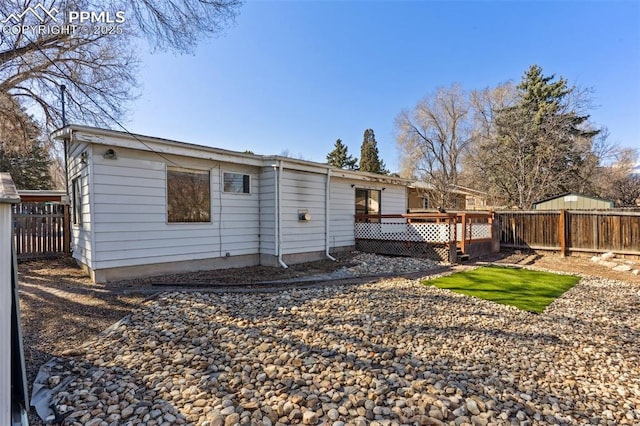 rear view of house with fence and a wooden deck