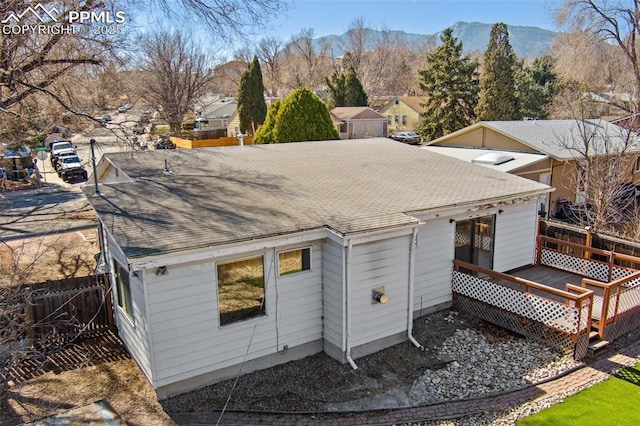 back of house featuring a deck with mountain view, fence, and roof with shingles