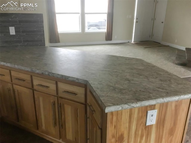 kitchen featuring open floor plan, light countertops, baseboards, and decorative backsplash