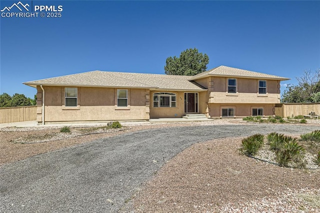 tri-level home with fence and stucco siding