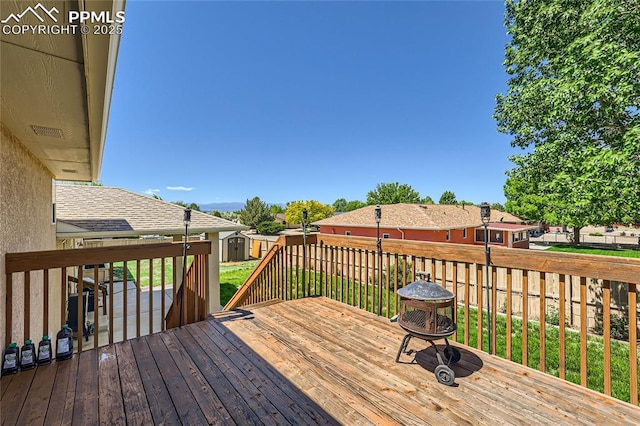 deck with an outdoor fire pit, a fenced backyard, a residential view, an outdoor structure, and a shed