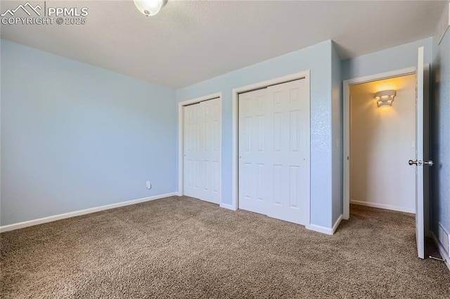 unfurnished bedroom with carpet, baseboards, and multiple closets