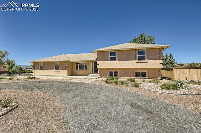 tri-level home featuring fence and stucco siding