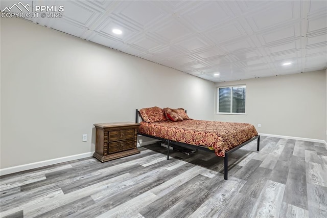 bedroom with baseboards, wood finished floors, and recessed lighting