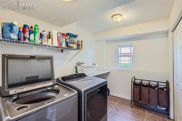 laundry room with laundry area, washer and dryer, and dark tile patterned flooring