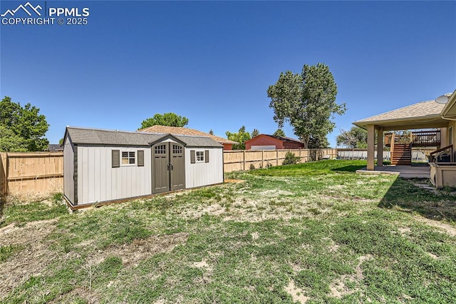 view of yard with a fenced backyard, a storage unit, and an outdoor structure