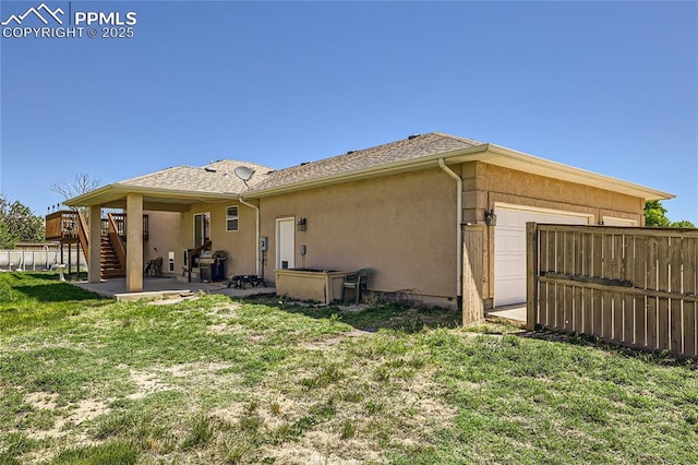 rear view of property featuring a patio, stucco siding, a lawn, fence, and stairs