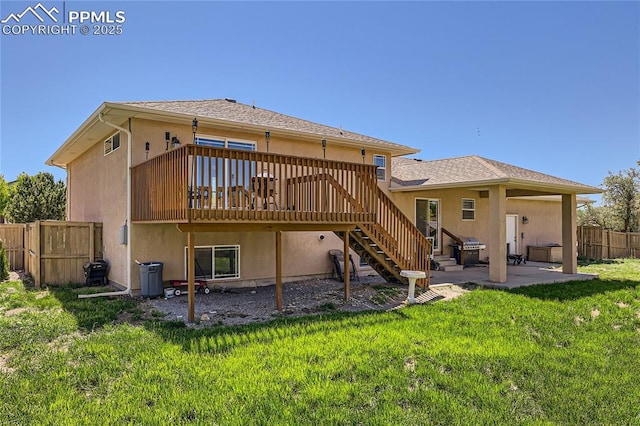 back of property with a lawn, fence, and stucco siding