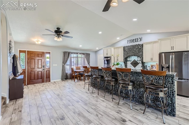 kitchen with cream cabinetry, stainless steel appliances, light wood-style flooring, vaulted ceiling, and ceiling fan